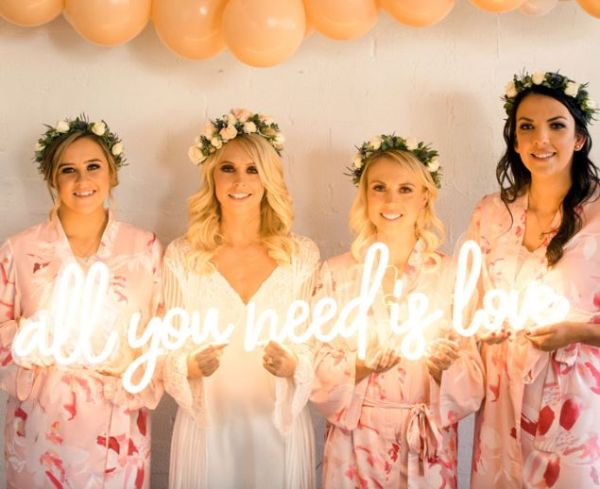 All You Need is Love neon LED light shown held by the bride and her bridesmaids before the wedding - from Custom Neon®
