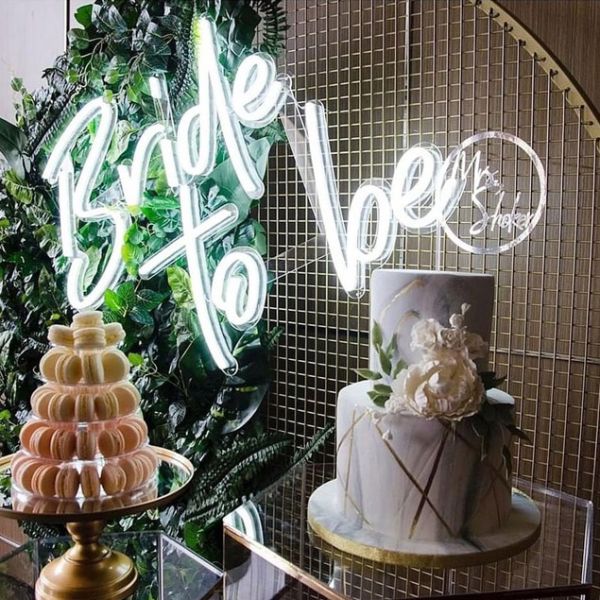 Large Bride to Be Wedding Sign in Bright LED Neon shown mounted on wire mesh behind the wedding cake - photo from CustomNeon.co.uk