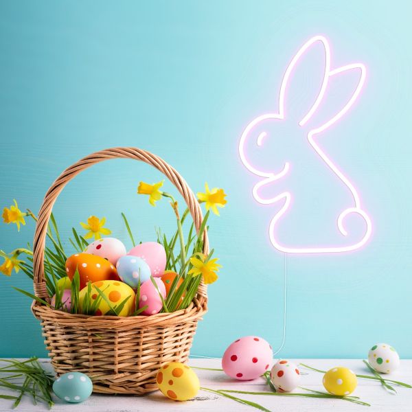 LED Neon Bunny Light in soft pink surrounded by an Easter basket and painted Easter eggs - by Custom Neon®