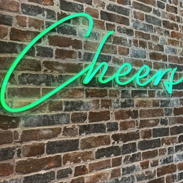 Cheers LED Neon Bar Sign in green on dark brick wall - Custom Neon®