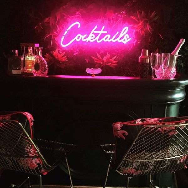Pink Custom Neon® Cocktails sign shown in a home bar @bezza32