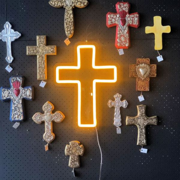 LED neon cross shown illuminated in yellow, wall mounted and surrounded by ornate crosses from Custom Neon®