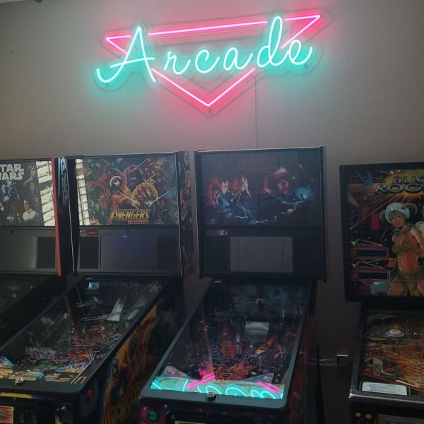 Custom Neon® LED arcade sign in pink and ice blue shown above retro pinball machines 