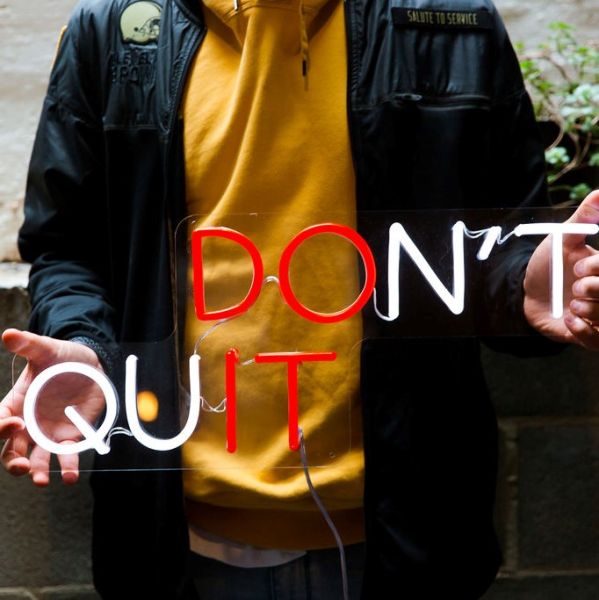 Don't Quit / Do It red and white neon sign held by a man @customneon