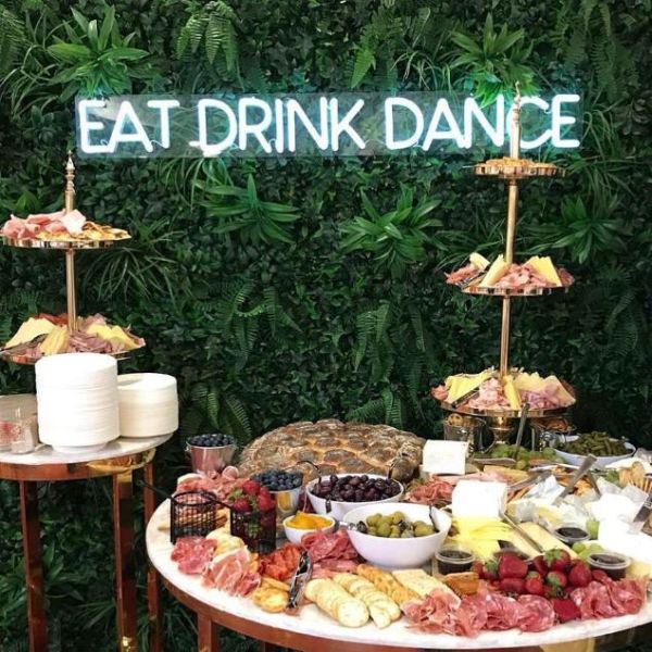 EAT DRINK DANCE LED neon sign on green wall behind grazing tables - from Custom Neon