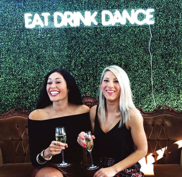 EAT DRINK DANCE Portable LED Neon Light Sign shown on a green wall at an Event - photo from CustomNeon.co.uk