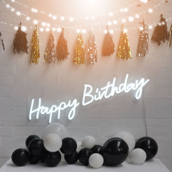 Happy Birthday illuminated sign from Custom Neon, shown on brick wall with party decorations. - Photo from CustomNeon.co.uk