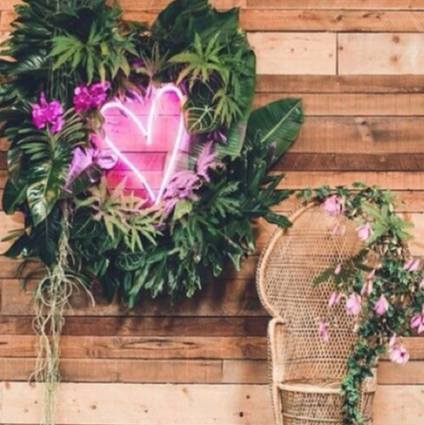 Pink LED neon love heart wall mounted amidst leaves at a special occasion made by @CustomNeon