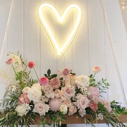 White love heart neon light wall mounted above roses at a special occasion - Custom Neon