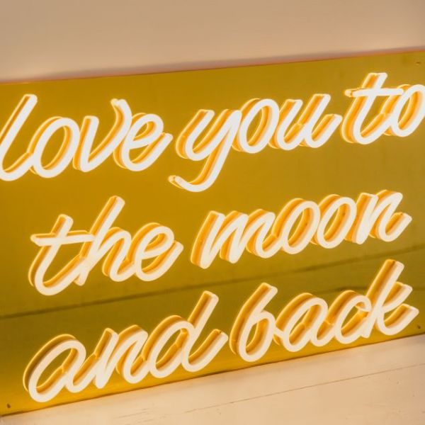 Love You To The Moon and Back warm white LED neon on gold mirrored acrylic backboard shown in bright light - CUSTOM NEON®