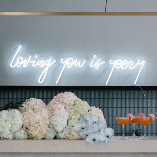 Loving you is yeezy LED neon wedding sign shown in white behind the bar - photo from CustomNeon.co.uk @customneon