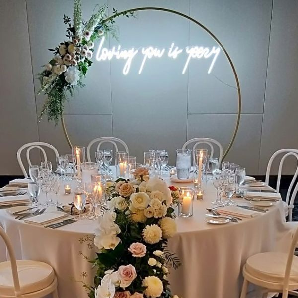Loving you is yeezy LED neon light shown attached to a floral arch behind the top table - photo from Custom Neon® @customneon