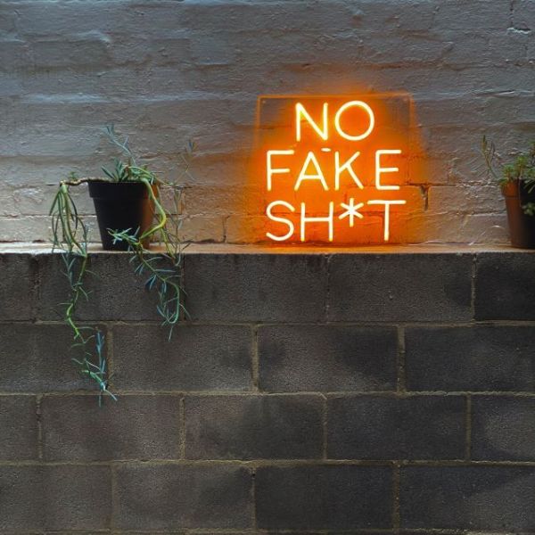 No Fake Shit neon look sign shown against a brick wall - by Custom Neon