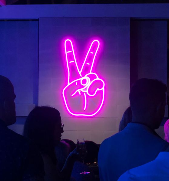 Neon Peace Sign aesthetic neon light shown wall mounted in a restaurant - photo from CustomNeon.com
