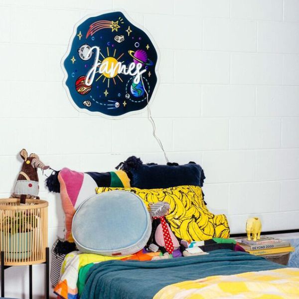 LED Neon Name Sign with a UV printed outer space background shown in child's bedroom - from Custom Neon by Neon Collective. 