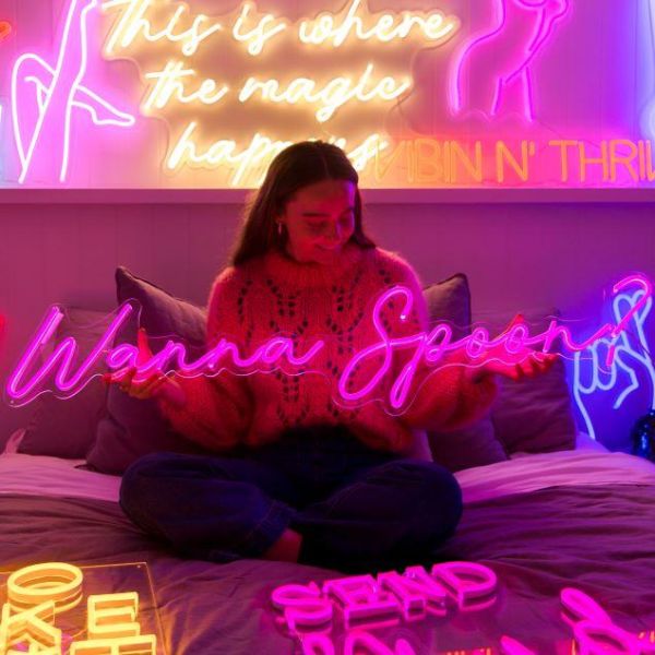 Wanna Spoon? Pink LED light sign shown illuminated on a couch - from Custom Neon
