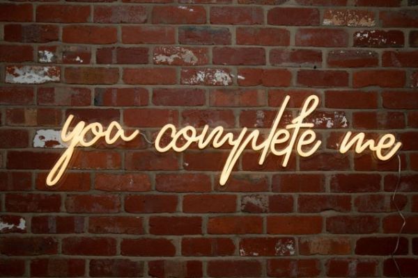 You Complete Me faux neon sign shown hung from a brick wall - Custom Neon®