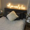All You Need is Love LED Neon Sign shown above a bed - photo from Custom Neon®