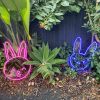 Custom Neon®  pink bunny face and blue bad bunny face shown as lighted decor for an Easter egg hunt