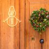 CUSTOM NEON® snowman light in white on a wooden door next to a Christmas wreath