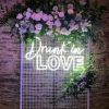 Drunk in LOVE LED neon sign shown on a mesh screen surrounded by floral decor - Custom Neon