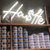 Hu$tle White Neon Sign on a shelf - photo from CustomNeon.com