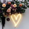 Love heart neon light in warm white wall mounted below floral decorations - Custom Neon