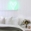 A little love heart in green shown as bedroom decor, on a shelf against a white wall - photo from CustomNeon.co.uk