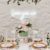 Love you xo white lightup sign on a white wall behind a wedding cake and table decor - from Custom Neon @customneon