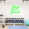 Rise and Grind green CUSTOM NEON® sign shown illuminated on white gym wall
