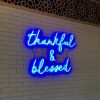 Thankful & Blessed blue neon sign shown illuminated on brick wall - made by @customneon for @9gramscafe 