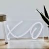 XO tabletop LED neon lamp shown on a wooden floor next to a plant - from Custom Neon®