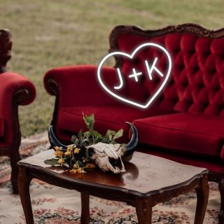 Custom Neon® white LED neon heart with initials on a red sofa in a rustic outdoor setting