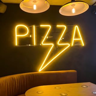 Custom Neon® yellow PIZZA arrow sign on dark wall above restaurant booth @lennoxpizza