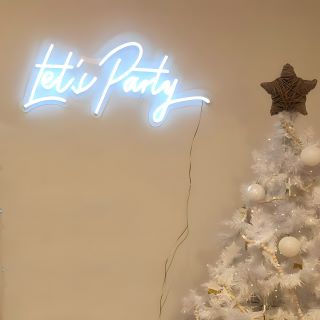 Custom Neon® white Let's Party sign behind white Christmas tree