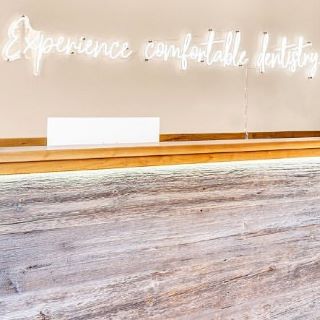 White Custom Neon® Experience Comfortable Dentistry sign behind reception @puredentalspa