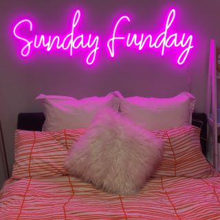 Pink Custom Neon® Sunday Funday sign above bed