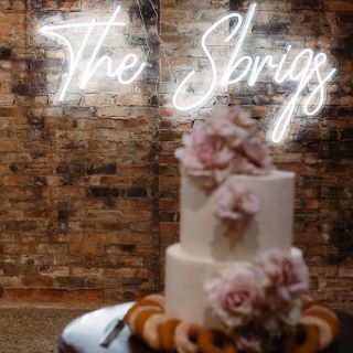 Custom Neon® last name sign with a wedding cake in the foreground