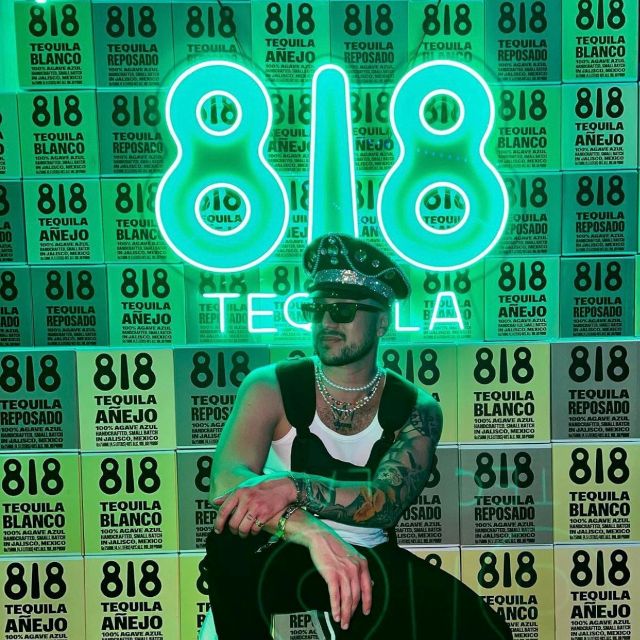 Person sitting in front of a green Custom Neon® '818 Tequila' Instagram wall