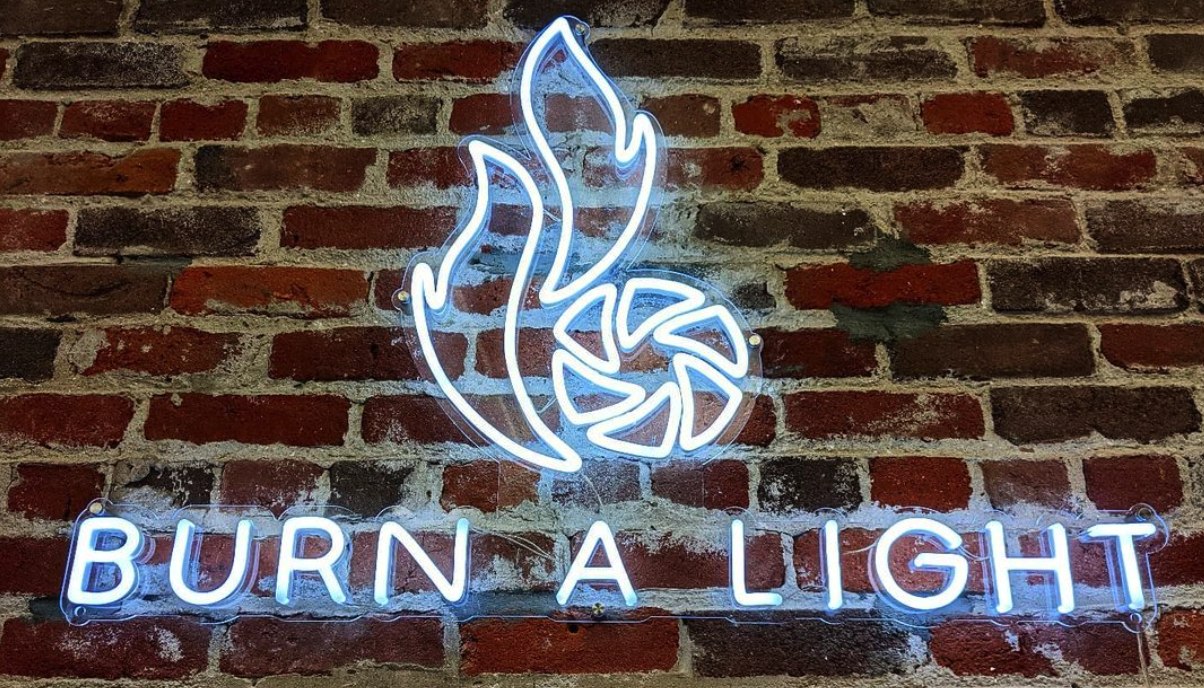 White Custom Neon® logo sign on a brick wall @burnalight