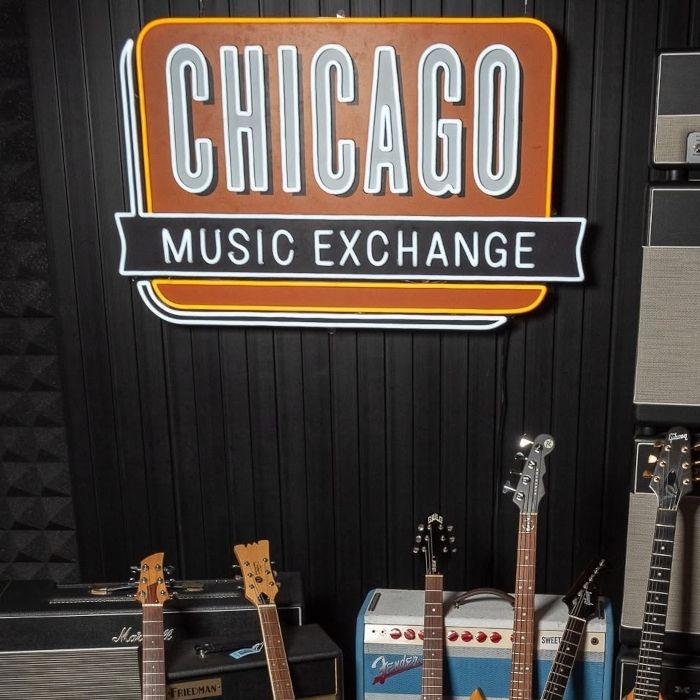 Close-up of the Chicago Music Exchange Custom Neon® sign mounted above guitar amps
