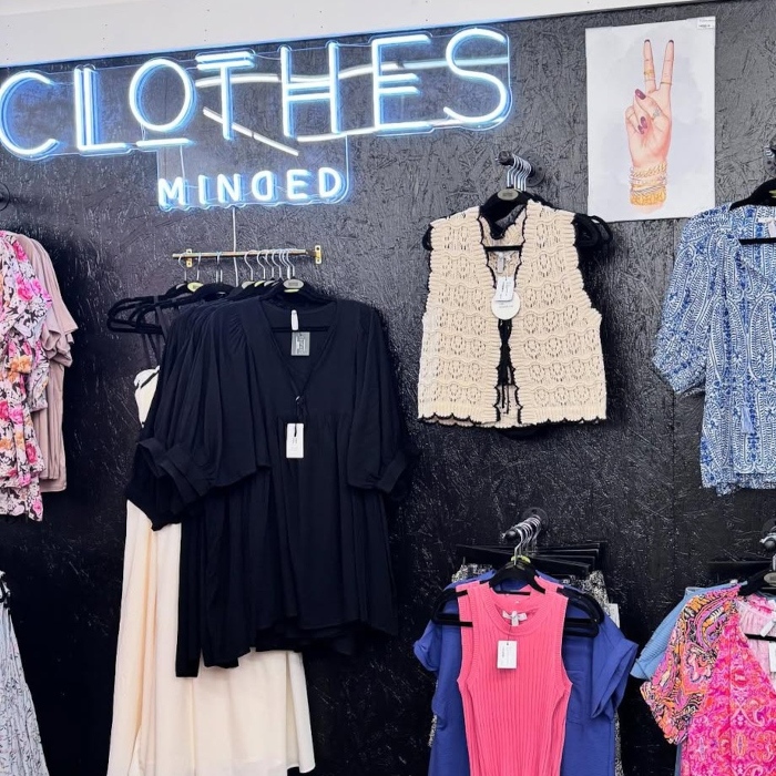 White LED Custom Neon® store sign on a grey wall above the merchandise @clothesmindedaz