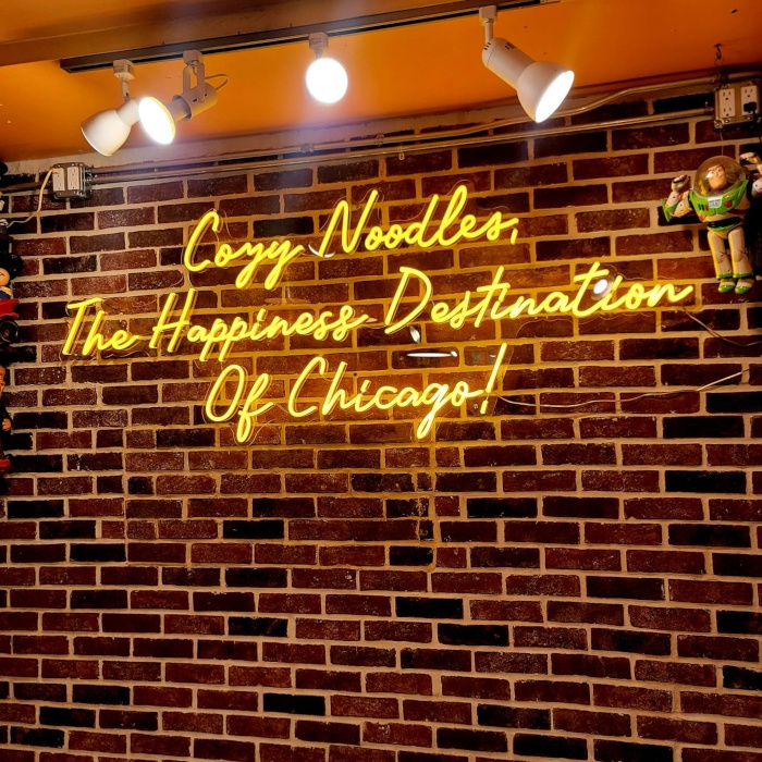 Yellow restaurant name sign on a brick wall by Custom Neon® @cozynoodles