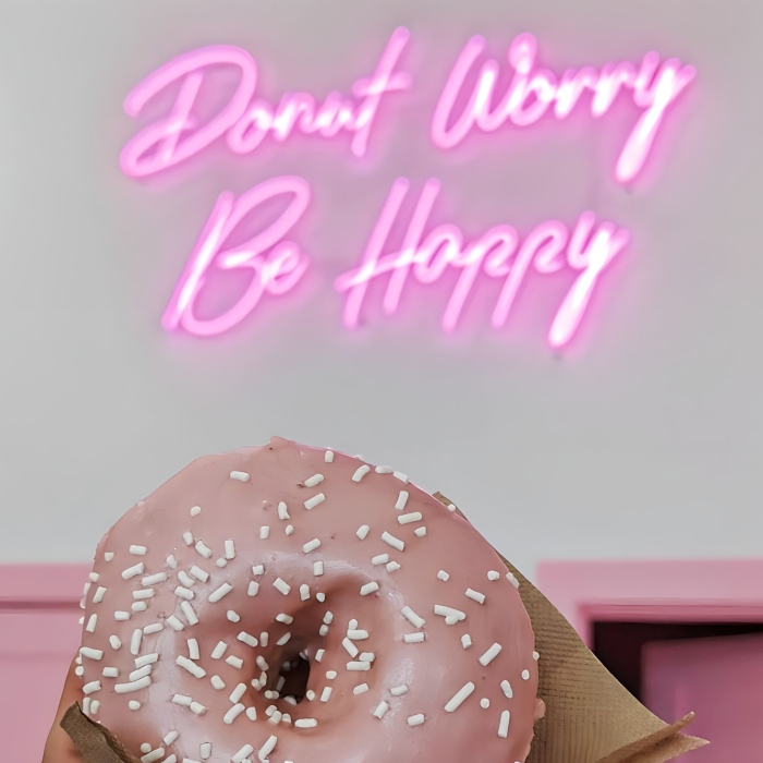 Donut worry be happy pink Custom Neon® sign on a white wall behind the counter @doughjoydonuts
