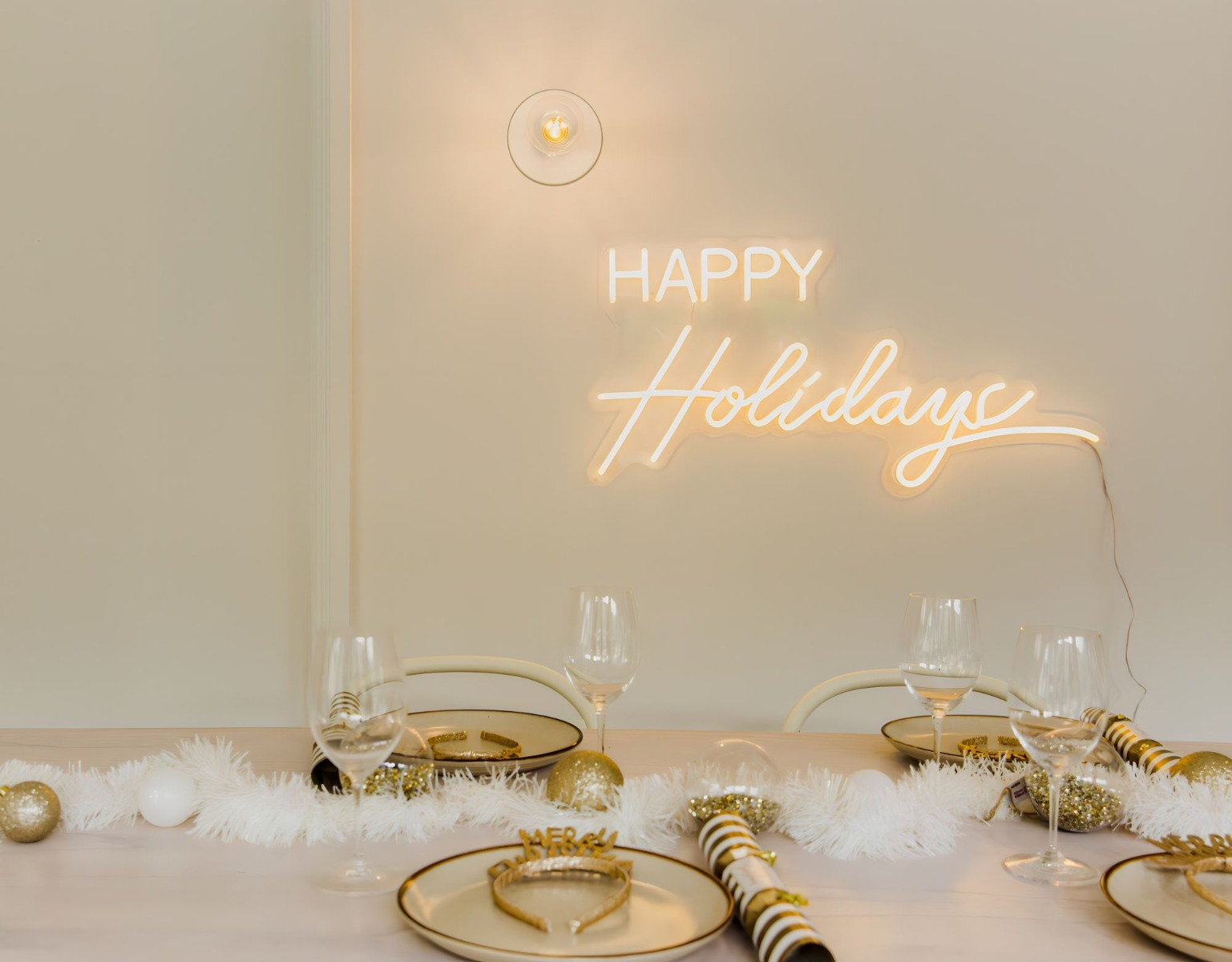 White Custom Neon® Happy Holidays sign above a dining room table laden with festive tableware and tinsel