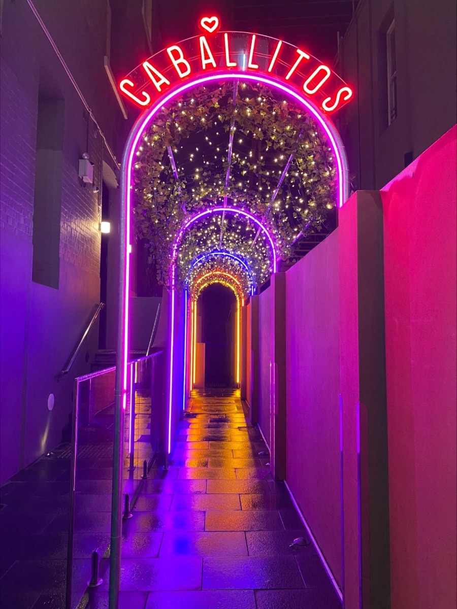 Pink red and purple Custom Neon® lights on an arch corridor