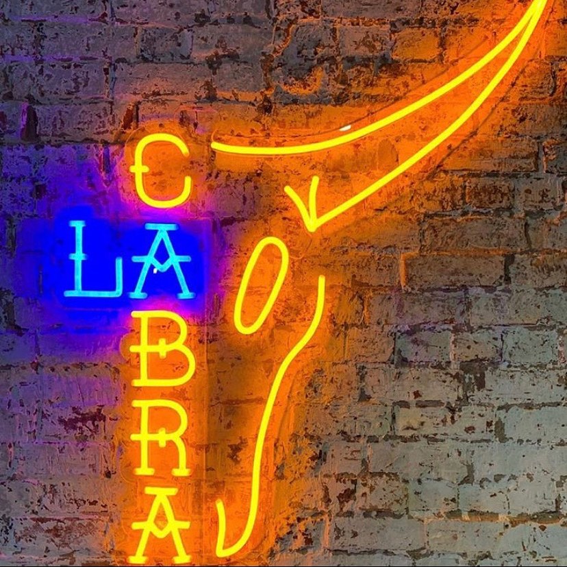 Custom Neon® restaurant logo on brick wall @lacabramexican