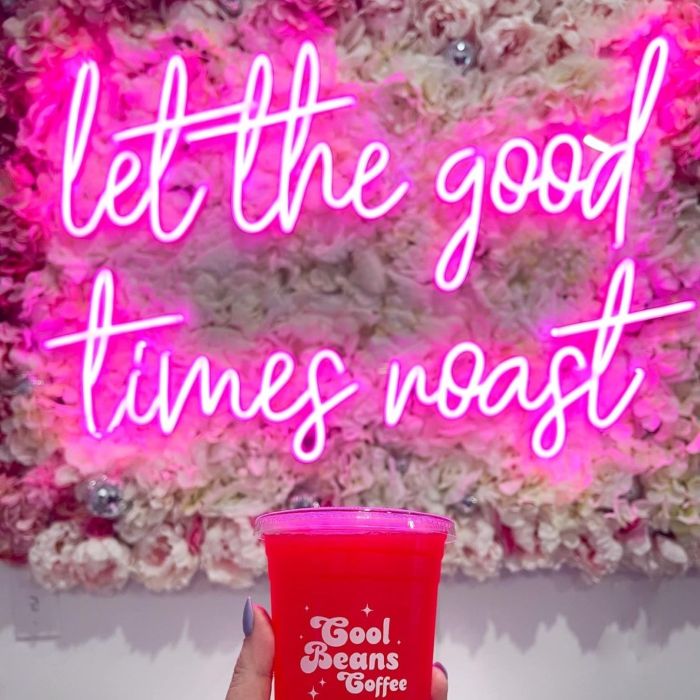 Custom Neon® pink tagline sign on a flower wall @coolbeanscoffee