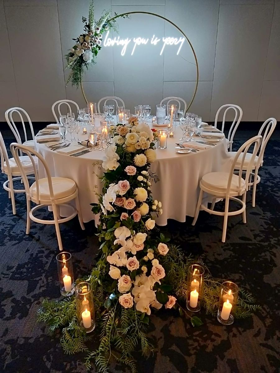 Custom Neon® white wedding sign hung on an arch behind the top table 
