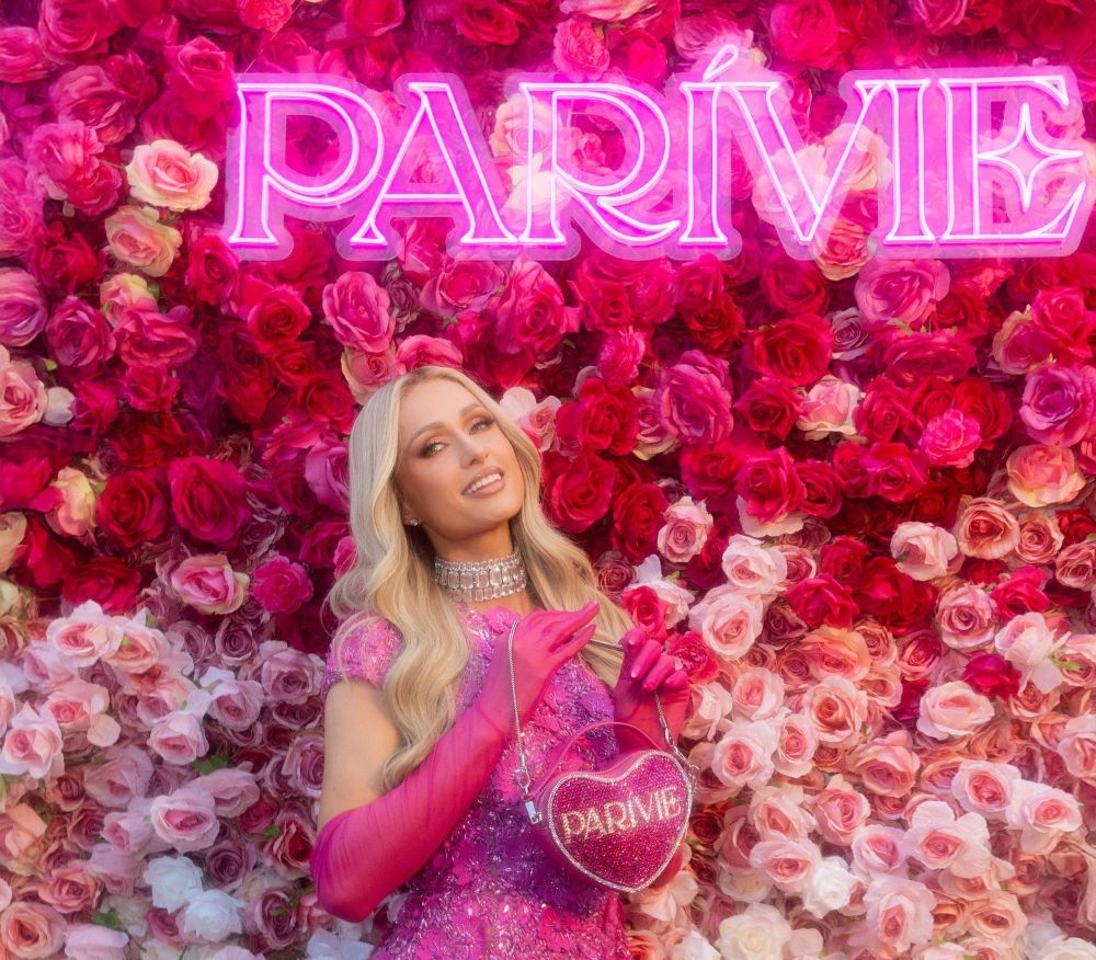 Pink Parivie sign by Custom Neon® on a rose wall with Paris Hilton in the foreground @parivie @parishilton